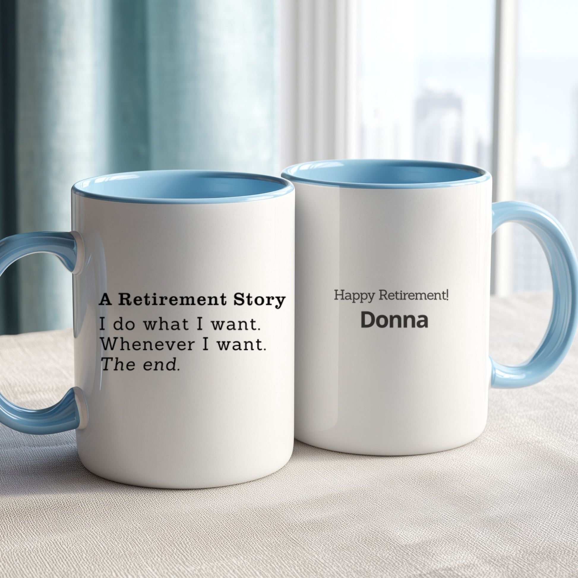 Two white mugs with a retirement message, with blue interior and handles on a light surface.